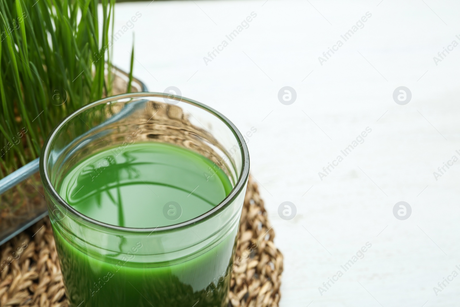 Glass of wheat grass juice on table, closeup. Space for text Photo of Glass of wheat grass juice on table, closeup. Space for text