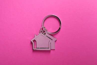 Photo of Metallic keychains in shape of houses on bright pink background, top view