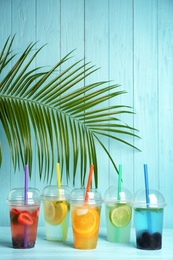 Photo of Plastic cups with lemonades on table against color background