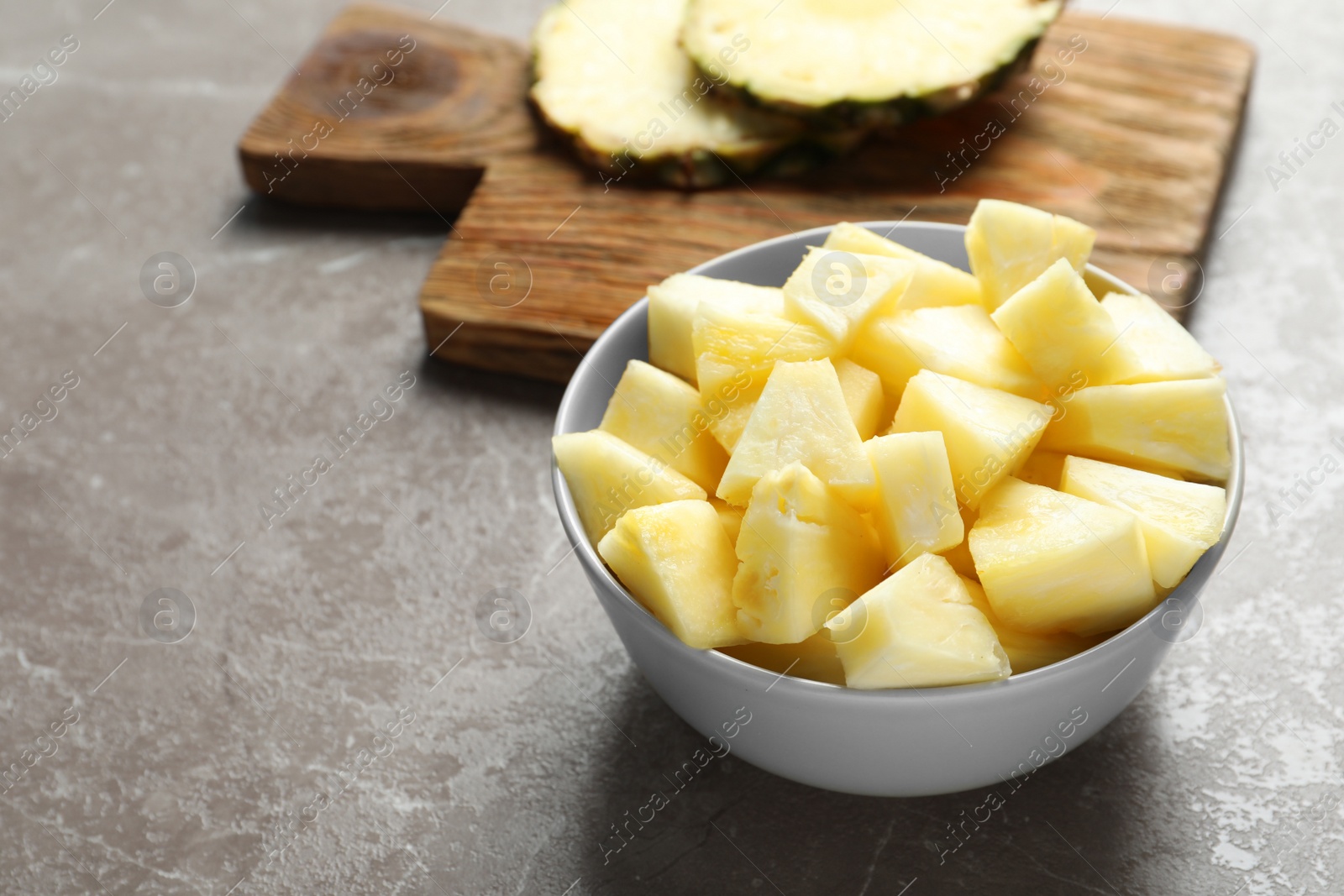 Photo of Bowl with fresh sliced pineapple on table