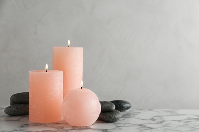 Photo of Composition of burning candles and spa stones on table. Space for text