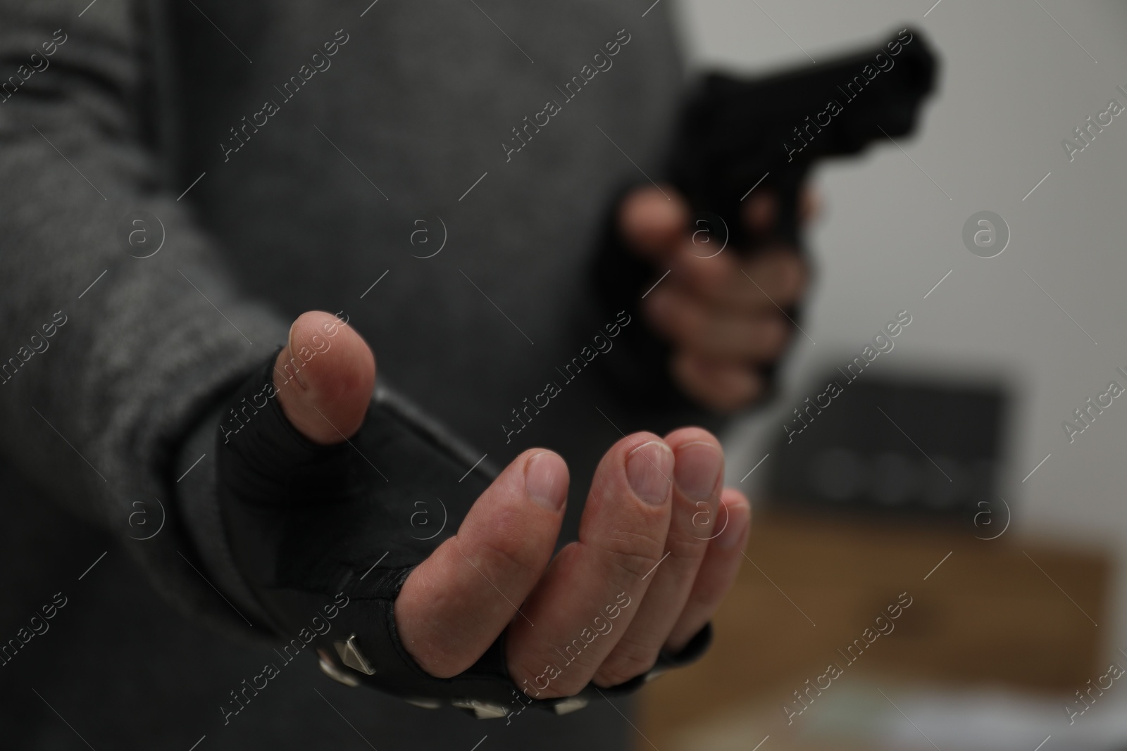 Photo of Dangerous criminal with gun indoors, closeup. Armed robbery