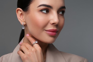 Young woman with elegant jewelry on dark grey background, closeup