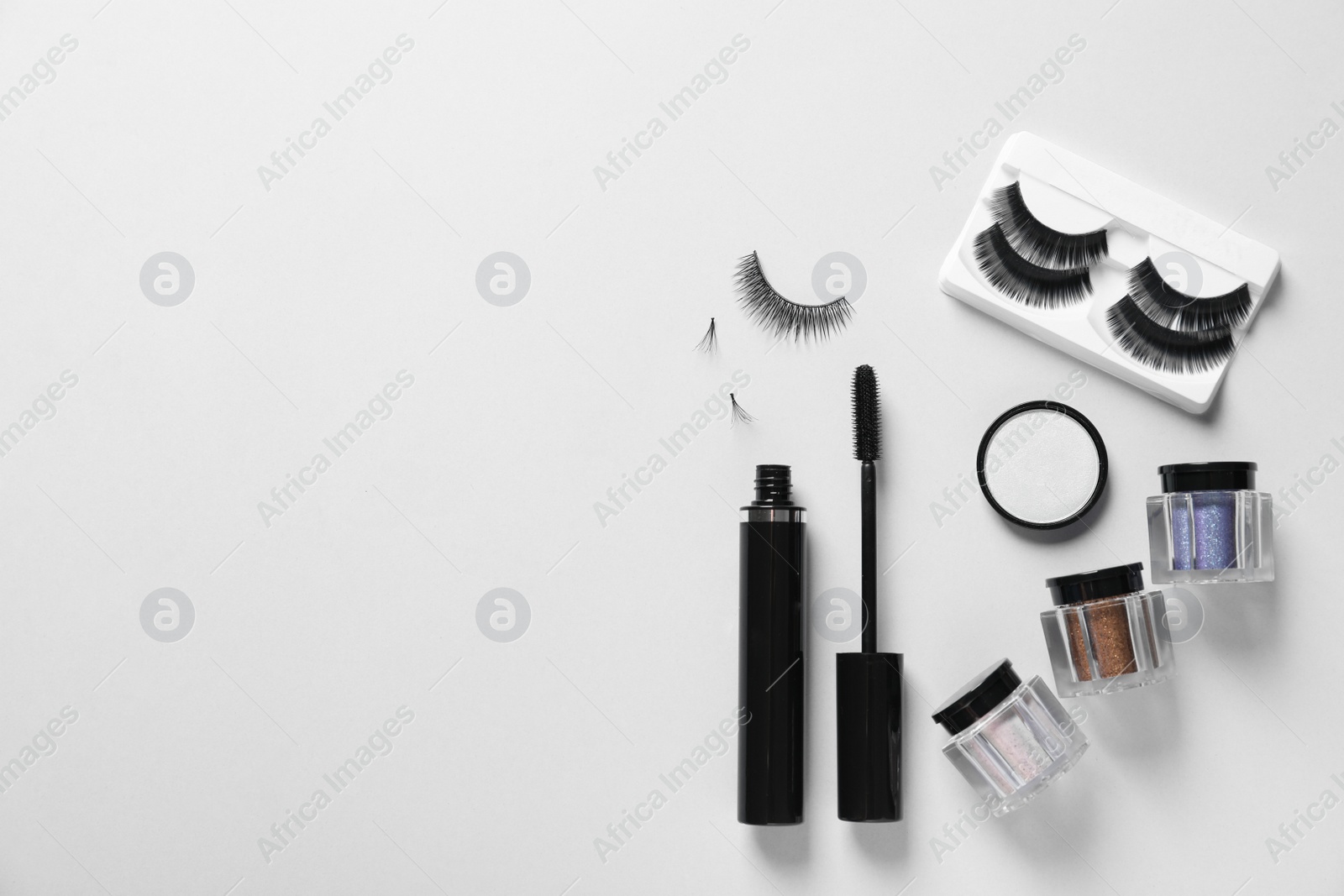 Photo of Composition with false eyelashes and other makeup products on white background, top view