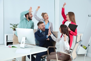 Photo of Group of office employees celebrating victory at workplace