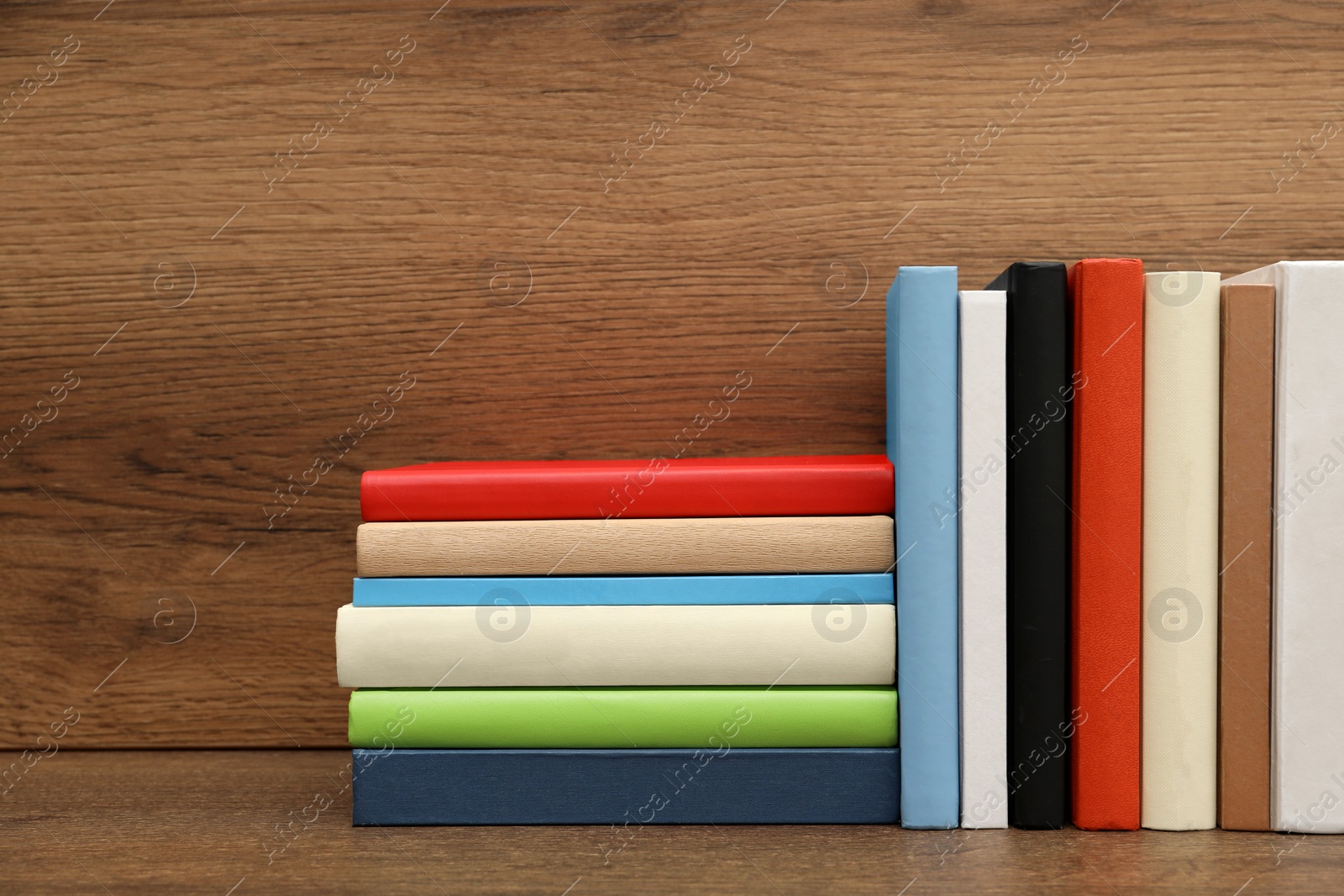 Photo of Many different hardcover books on wooden table. Space for text