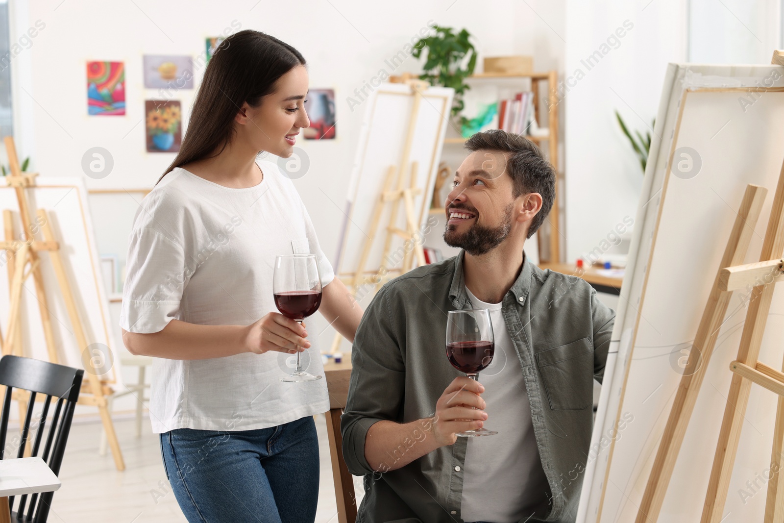 Photo of Artist and her student with glasses of wine having painting class in studio. Creative hobby