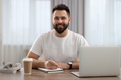 Young man watching webinar at table in room