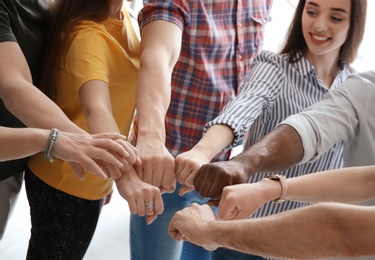 Photo of People putting hands together indoors. Unity concept