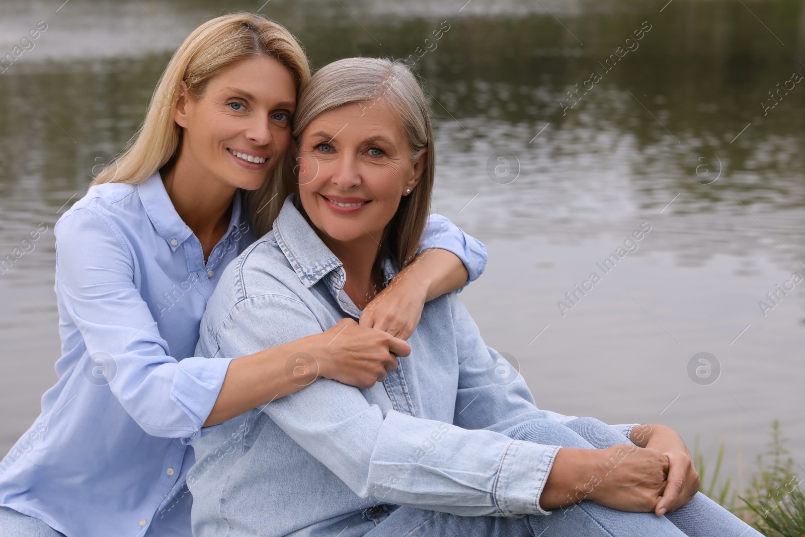 Photo of Happy mature mother and her daughter hugging near pond