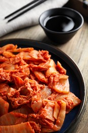 Delicious kimchi with Chinese cabbage and sauce on wooden table, closeup