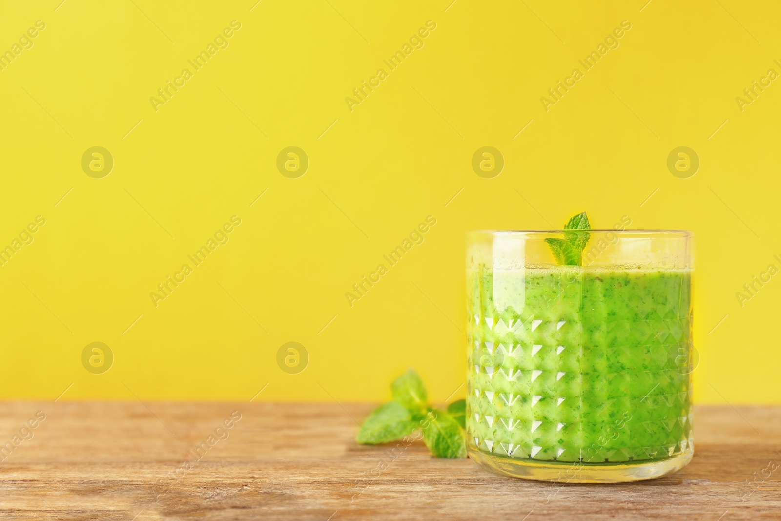 Photo of Glass with delicious detox smoothie on table against color background