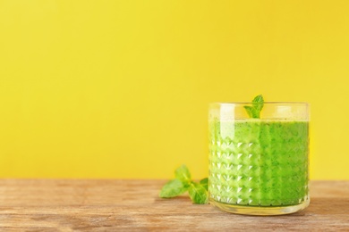 Glass with delicious detox smoothie on table against color background