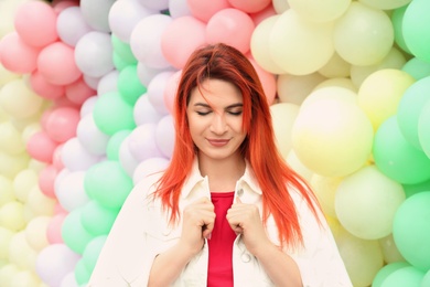 Photo of Young woman with bright dyed hair near colorful balloons