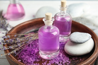 Bottles with natural herbal oil and lavender flowers on plate