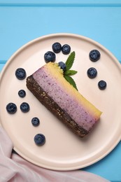 Photo of Delicious cheesecake with blueberry and mint on light blue wooden table, top view