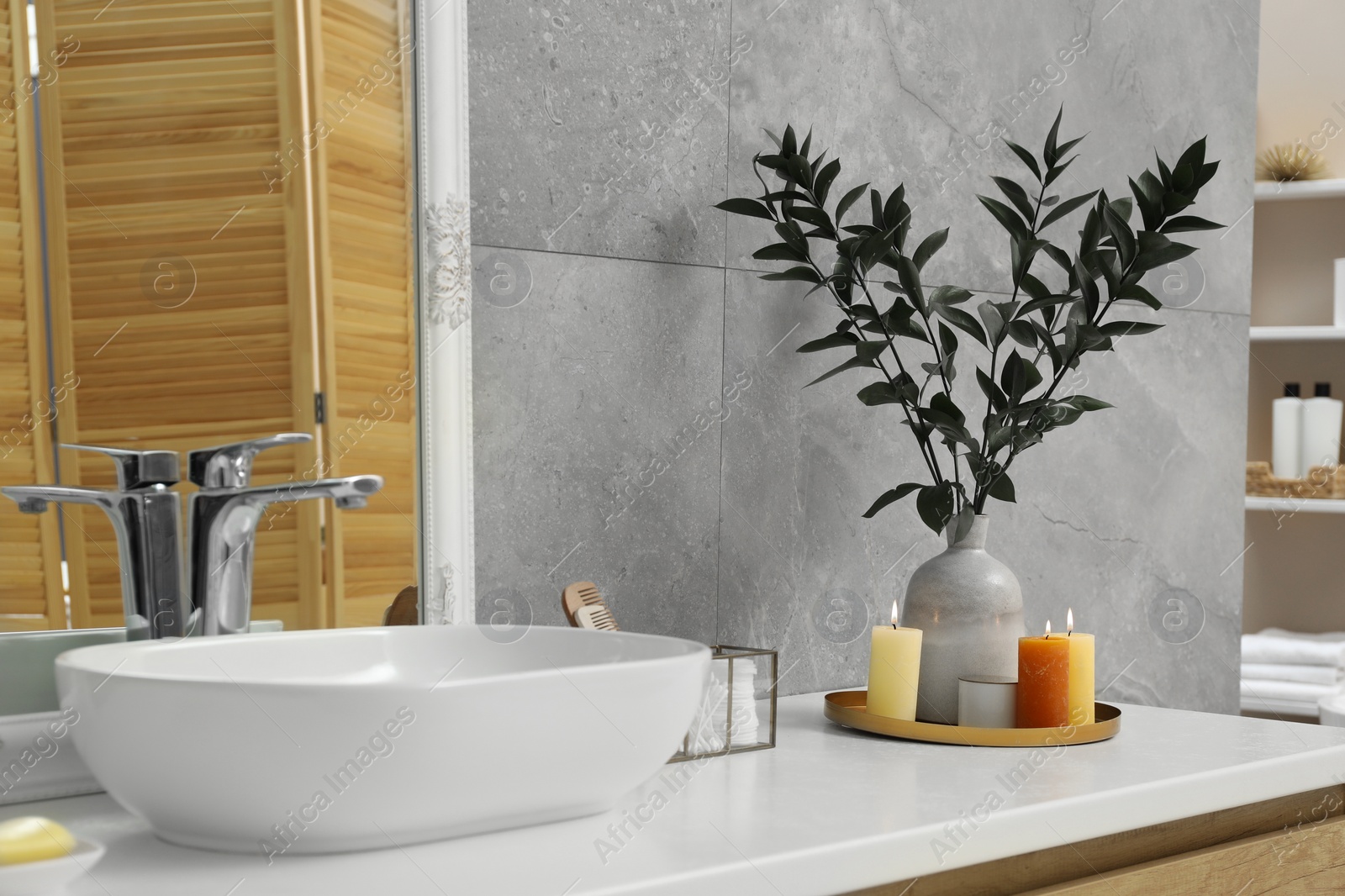 Photo of Beautiful plant in vase and burning candles near vessel sink on bathroom vanity