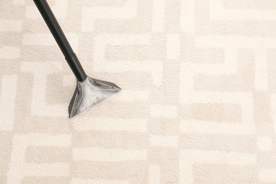 Removing dirt from carpet with vacuum cleaner indoors, closeup. Space for text