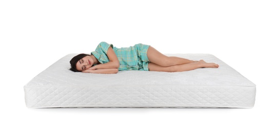 Young woman lying on mattress against white background