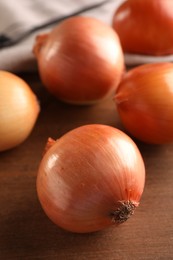 Photo of Many ripe onions on wooden table, closeup