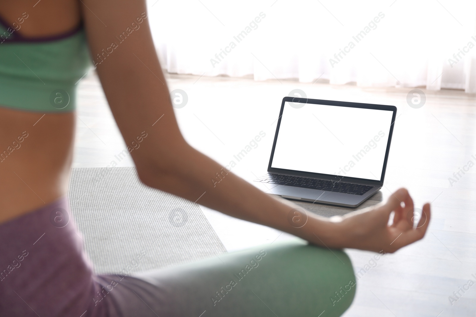 Photo of Woman having online video class via laptop at home, closeup. Distance yoga course during coronavirus pandemic