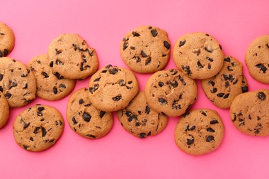 Photo of Many delicious chocolate chip cookies on pink background, flat lay