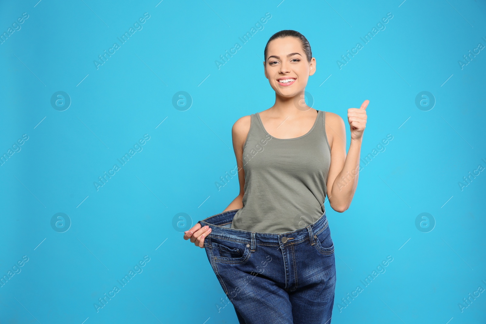 Photo of Slim woman in oversized jeans on color background, space for text. Weight loss