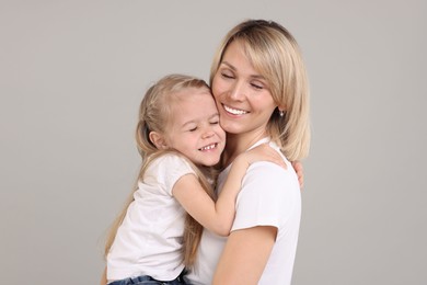 Family portrait of happy mother and daughter on grey background