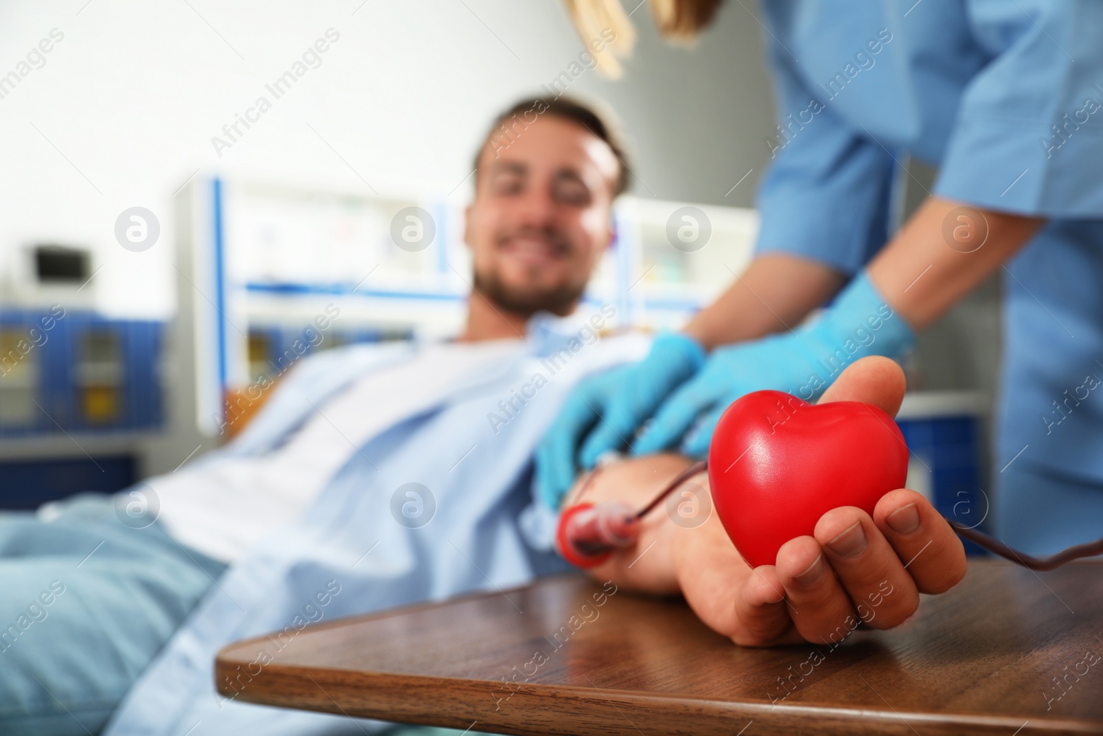 Photo of Young man making blood donation in hospital, focus on hand