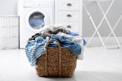 Wicker basket with dirty laundry on floor indoors