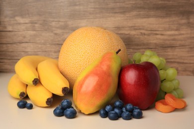 Photo of Delicious ripe fruits, blueberries and dried apricots on beige table, closeup