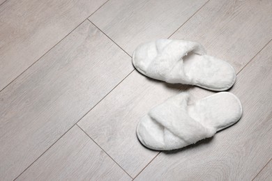 Photo of Pair of soft slippers on wooden floor, above view. Space for text