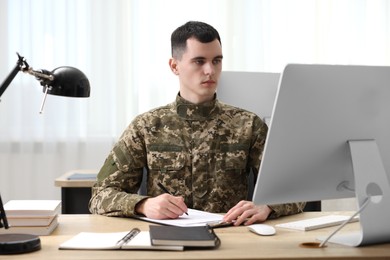 Military service. Young soldier working at wooden table in office