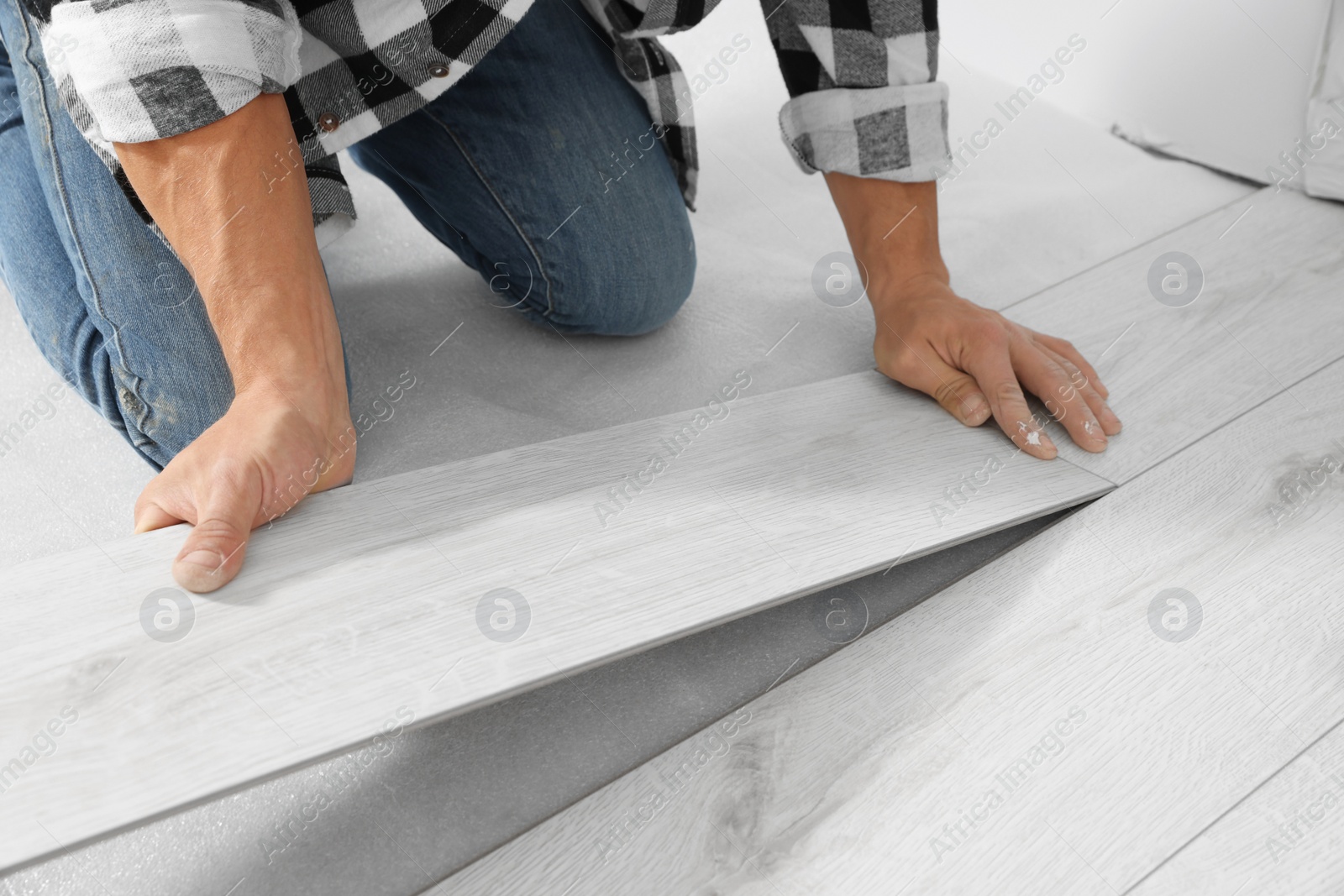 Photo of Professional worker installing new laminate flooring indoors, closeup