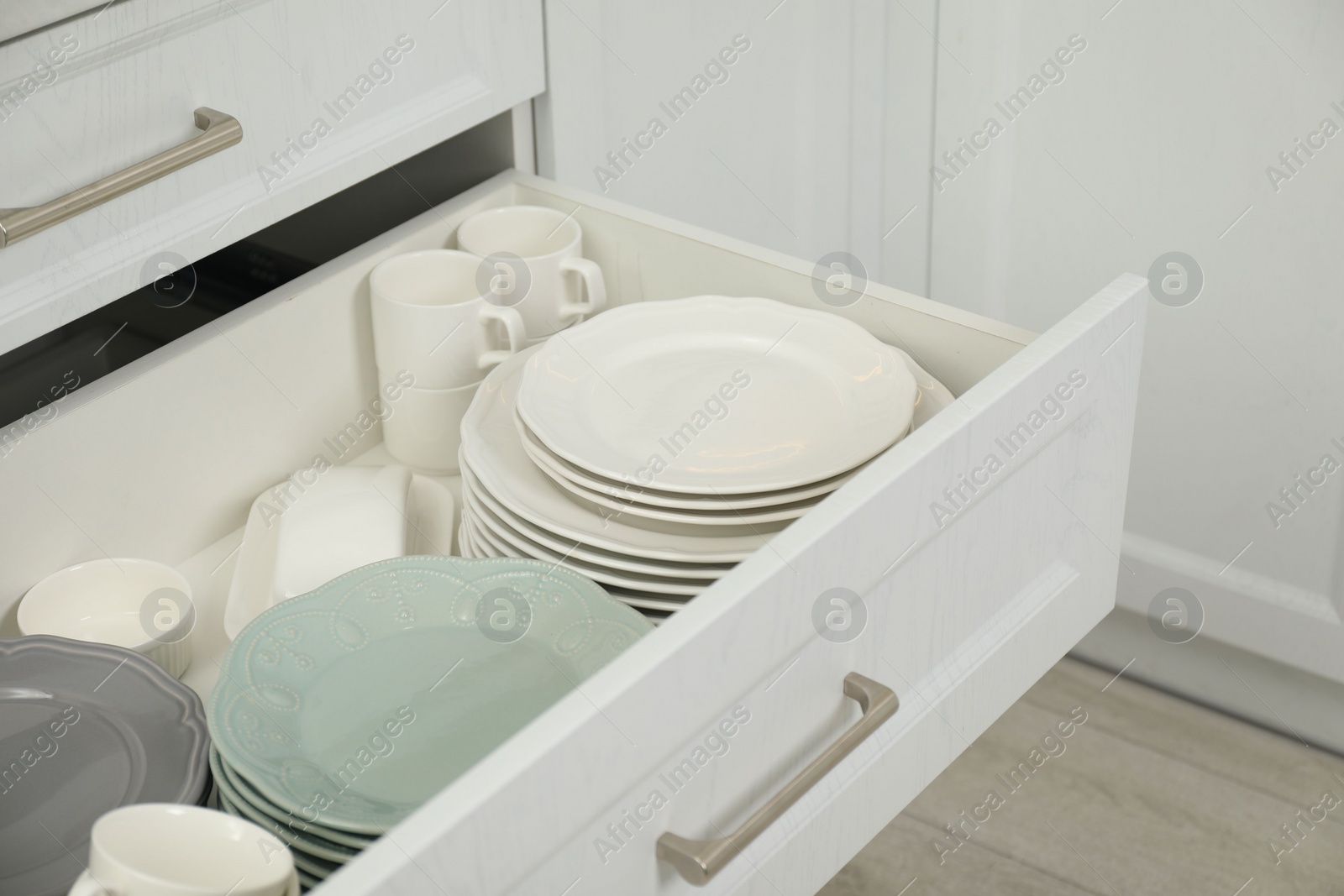 Photo of Clean plates, cups and bowl in drawer indoors