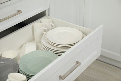 Clean plates, cups and bowl in drawer indoors