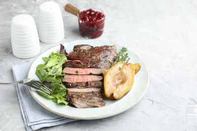 Photo of Delicious roasted beef meat, caramelized pear and greens served on light textured table. Space for text