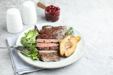 Delicious roasted beef meat, caramelized pear and greens served on light textured table. Space for text