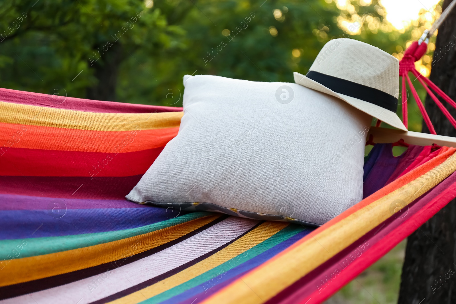 Photo of Comfortable bright hammock with soft pillow and hat at green garden, closeup