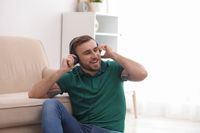 Photo of Young man in headphones enjoying music at home