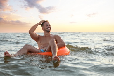 Happy young man on inflatable ring in water