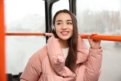 Beautiful young woman listening to music with headphones in public transport