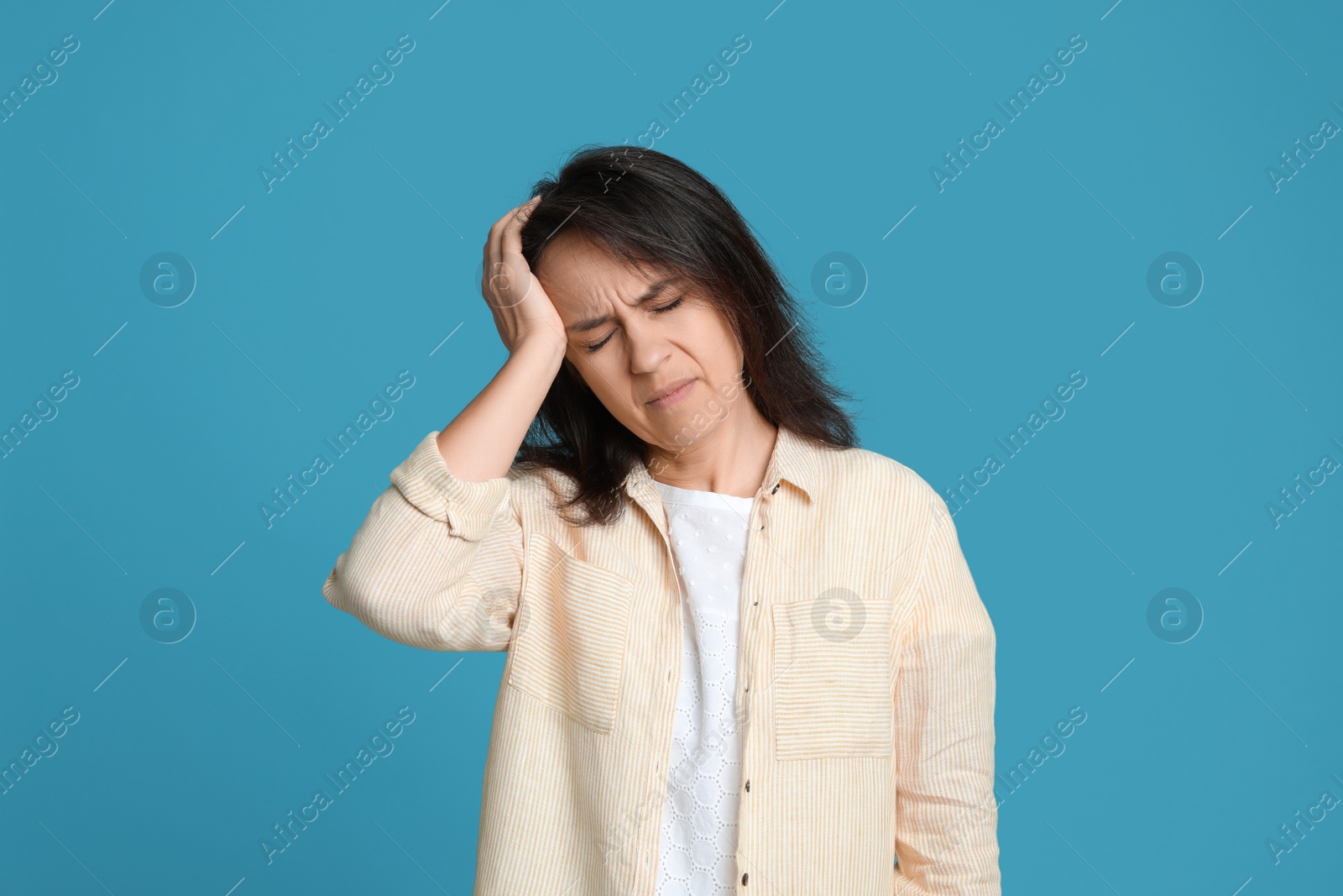 Photo of Mature woman suffering from headache on light blue background