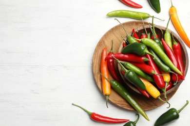 Photo of Different chili peppers on white wooden table, flat lay. Space for text