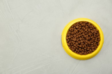 Photo of Dry food in pet bowl on grey background, top view. Space for text