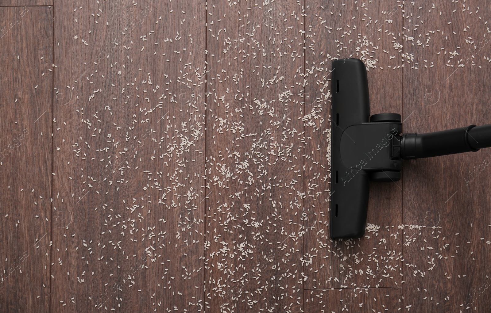 Photo of Vacuuming scattered rice from wooden floor, top view. Space for text