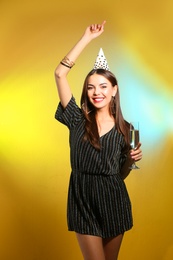 Portrait of happy woman with party hat and champagne in glass on color background