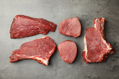 Photo of Flat lay composition with different fresh beef cuts on grey table