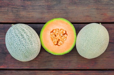 Whole and cut fresh ripe melons on wooden table, flat lay