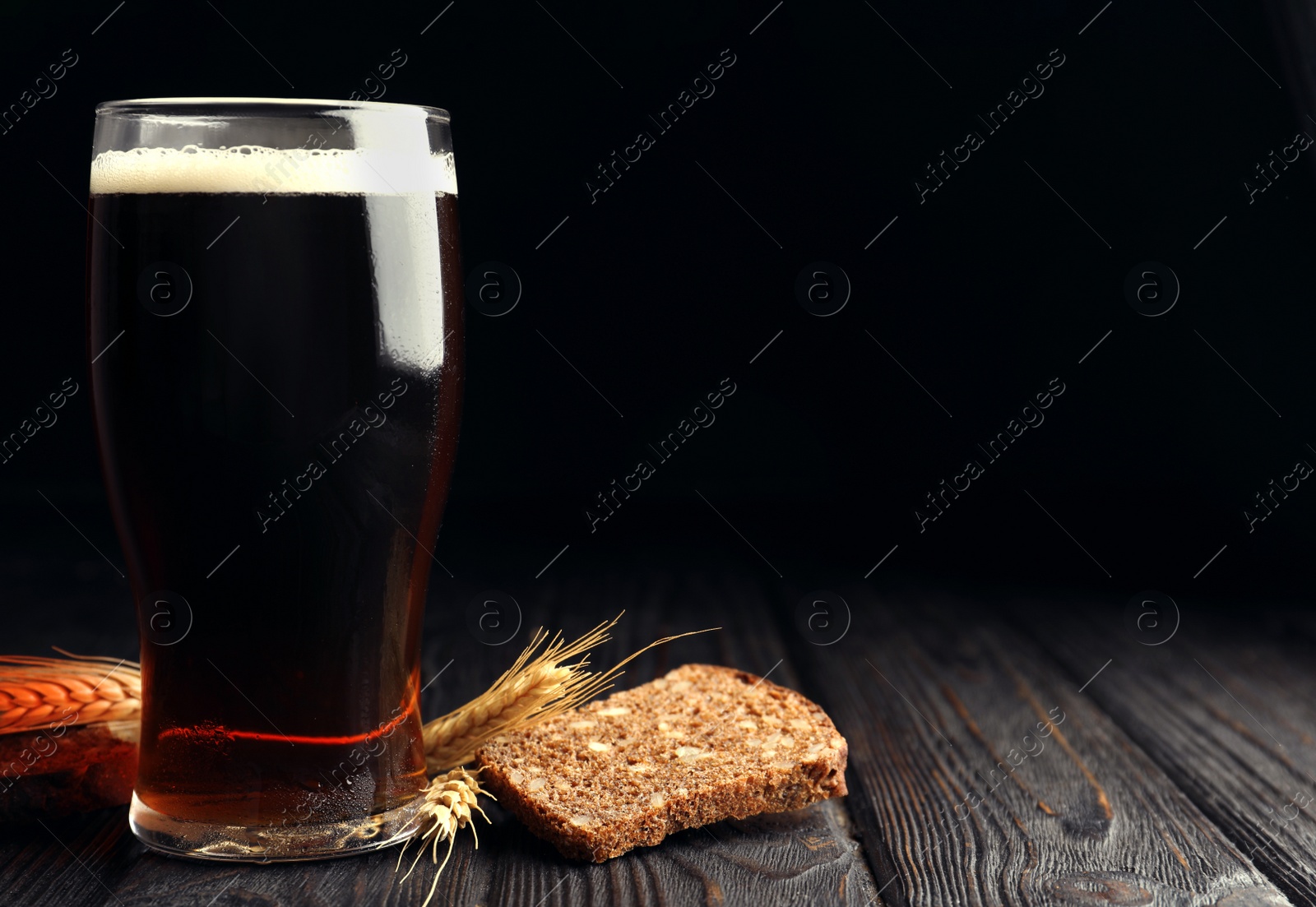 Photo of Delicious kvass, bread and spikes on wooden table. Space for text